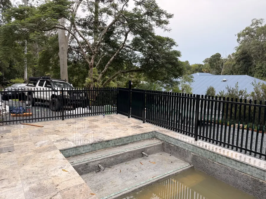 Black aluminium flat-top pool fence around a new in-ground pool under construction