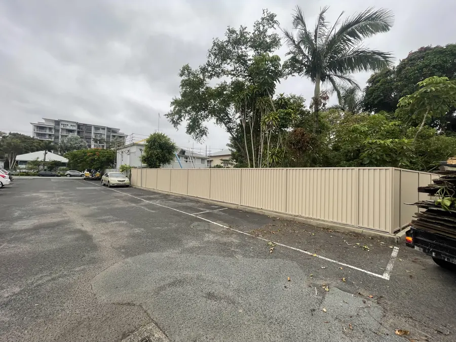 Cream Colorbond boundary fence enclosing a commercial car park