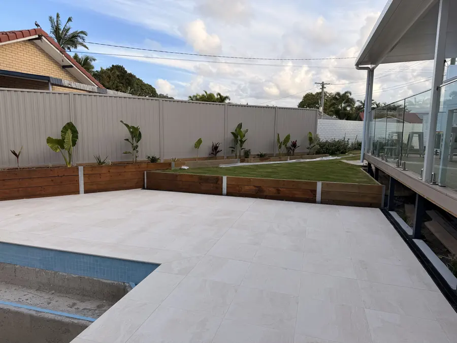 Colorbond boundary fence and timber sleeper garden beds around a new pool and patio