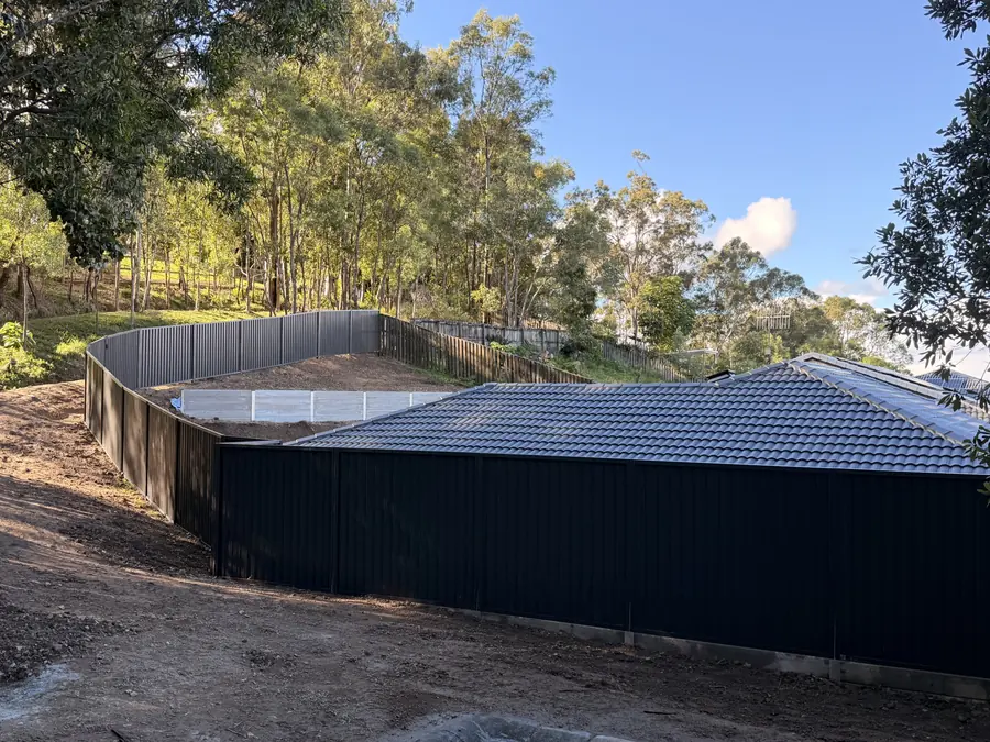 Charcoal Colorbond fence curving around a large acreage boundary