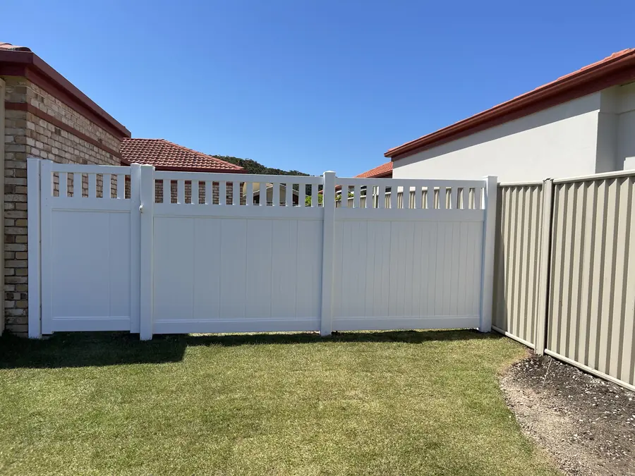 White PVC privacy fence with a square lattice top section beside a Colorbond boundary