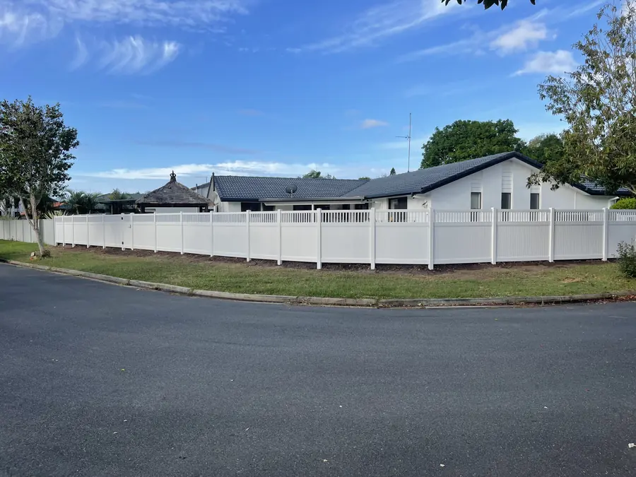 White PVC privacy fence with picket top wrapping a corner block frontage