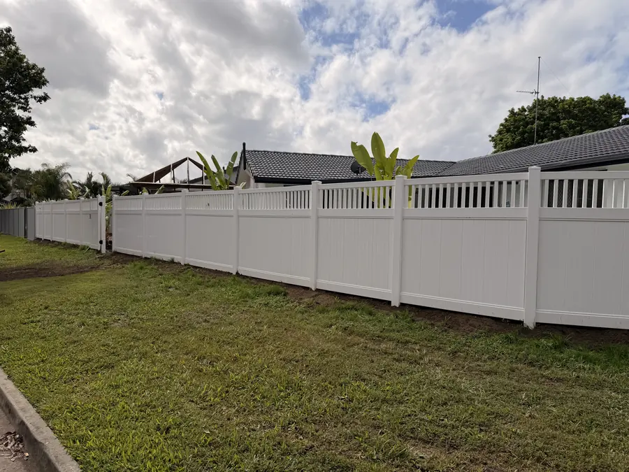 White PVC privacy fence with lattice top curving around a corner block