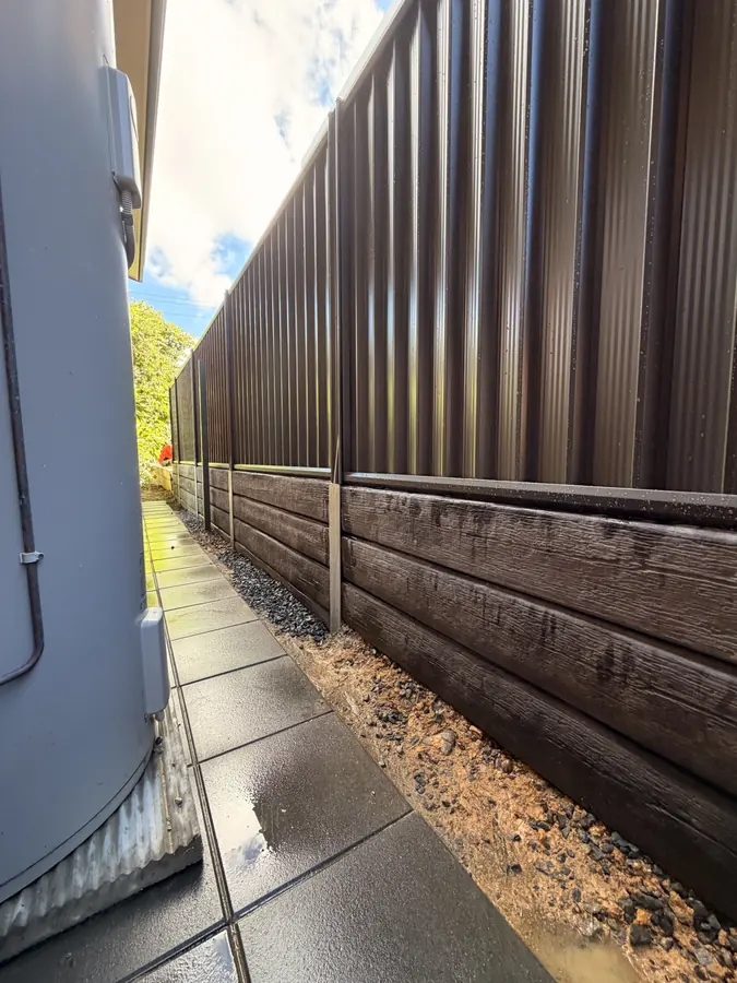 Woodgrain sleeper retaining wall with galvanised posts and a Colorbond fence above