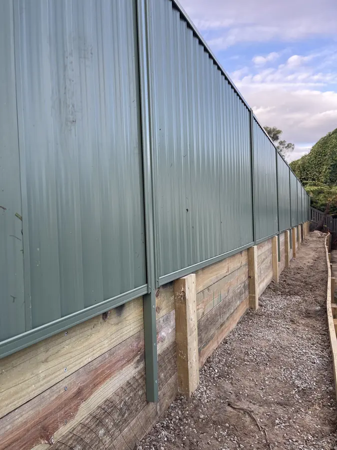 Pale green Colorbond fence built on top of a treated pine sleeper retaining wall