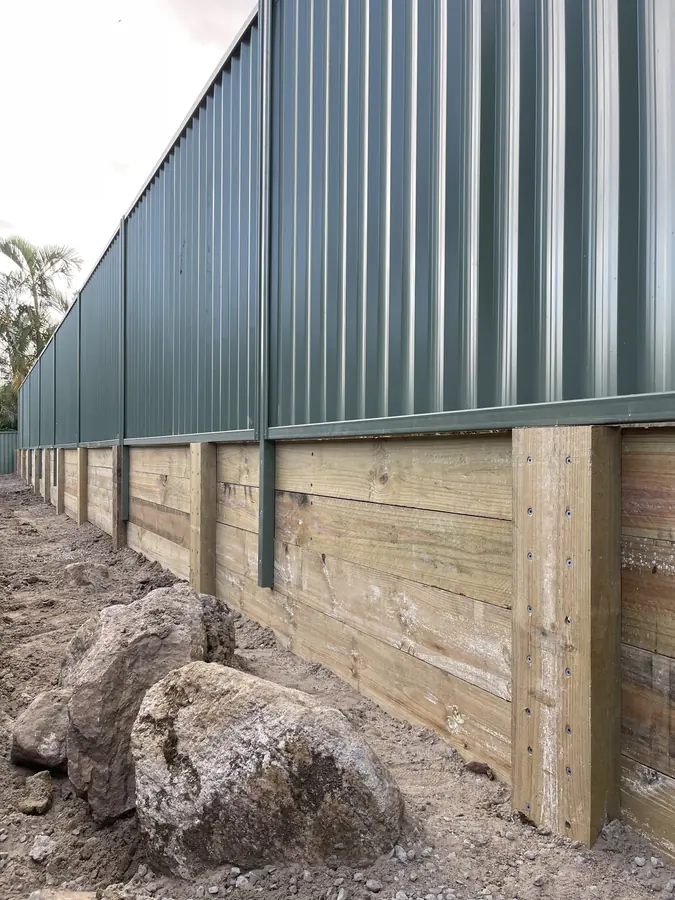 Treated pine sleeper retaining wall with galvanised posts supporting a Colorbond fence