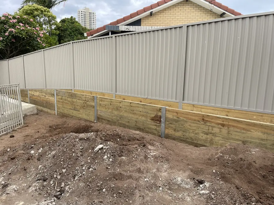 Cream Colorbond fence above a new treated pine sleeper retaining wall