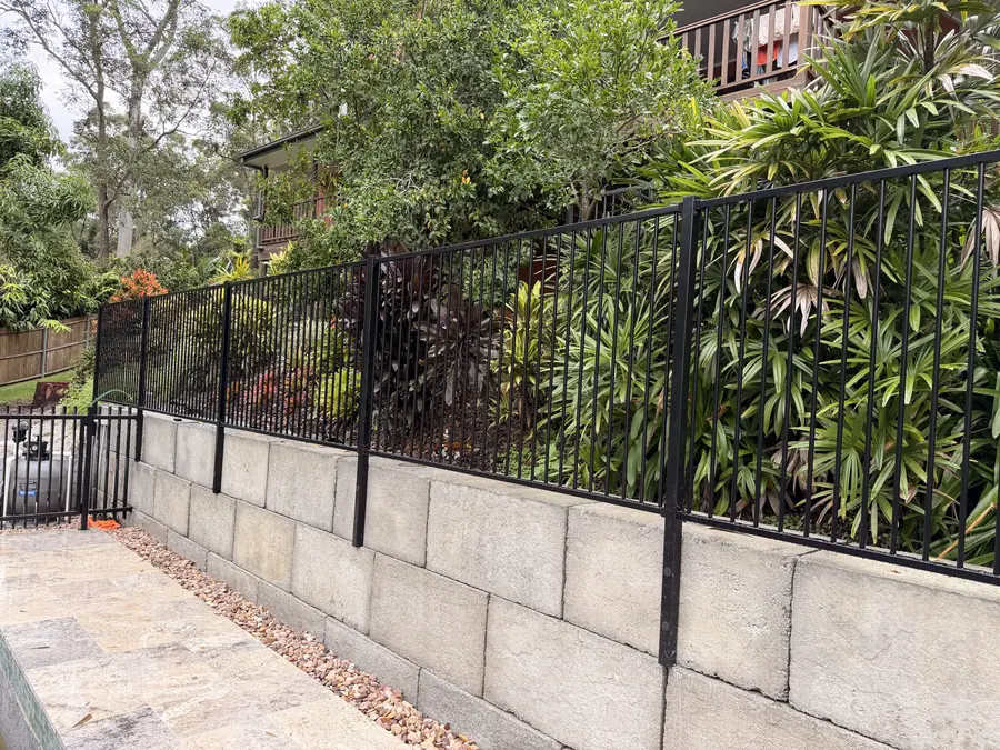 Besser block retaining wall topped with black aluminium flat-top fencing