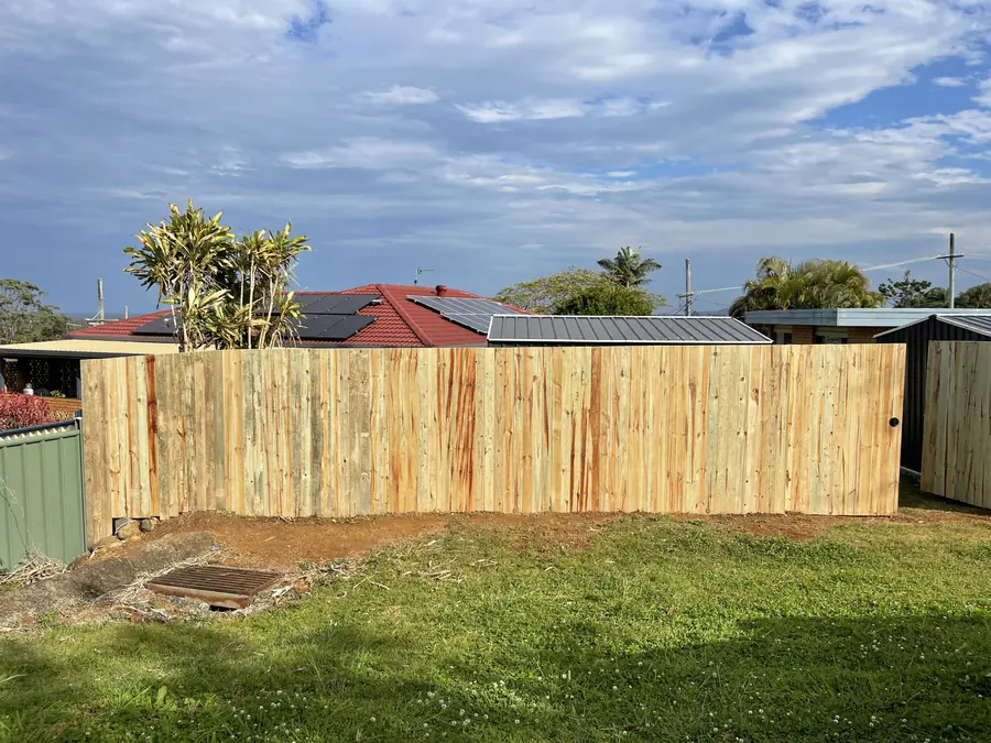 New treated pine butted paling fence along a sloping backyard boundary