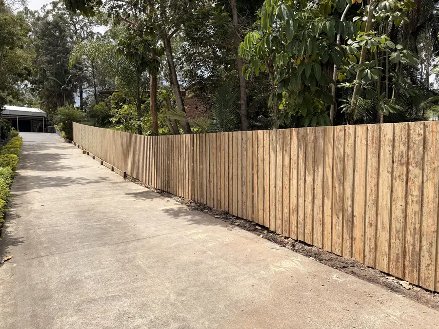Treated pine paling fence stepping down a long driveway boundary