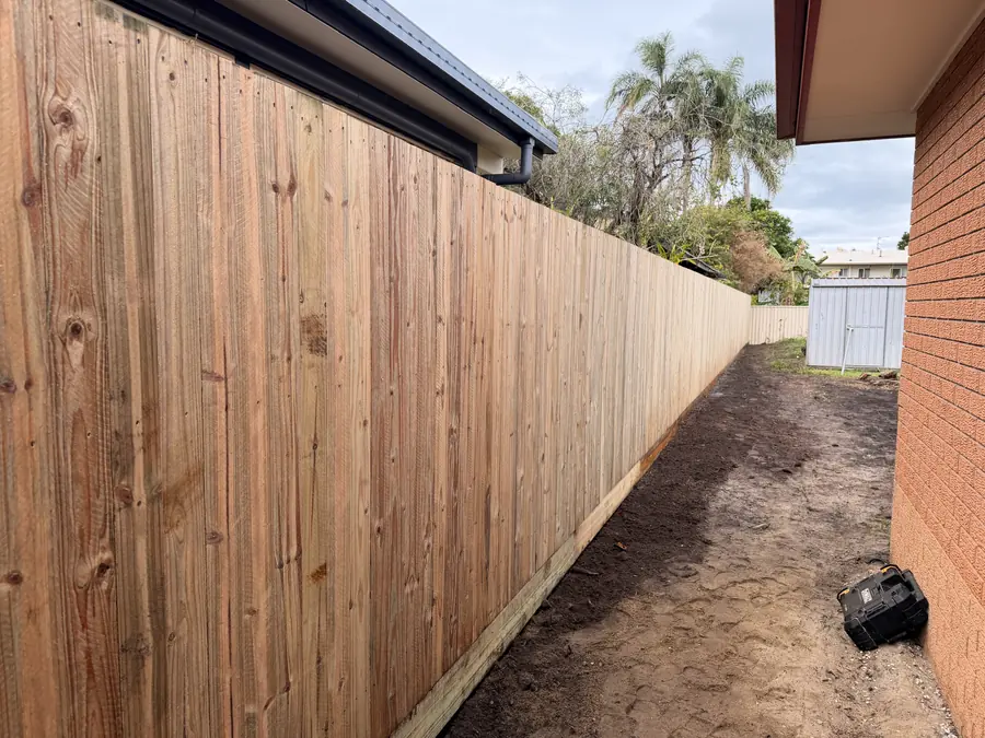 Treated pine paling fence along a narrow side boundary beside a brick home